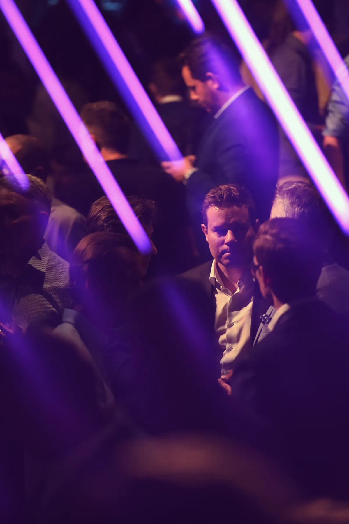 Executives in conversation at AssetRush, lit by purple light